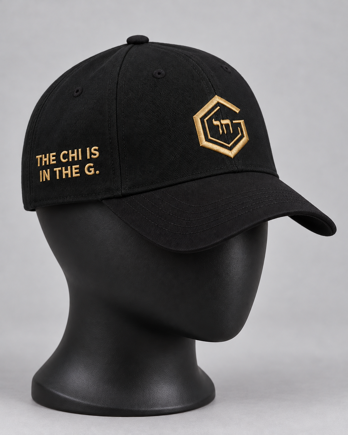 Black Architect cap on a matte-black display form; planned gold G and Chai front embroidery and The Chi Is in the G side lettering.