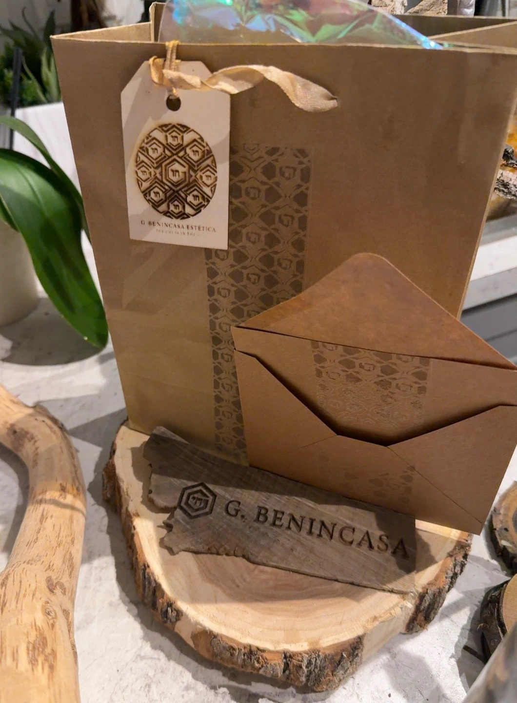 Kraft bag, envelope, tag and engraved wood nameplate arranged as a packaging study.