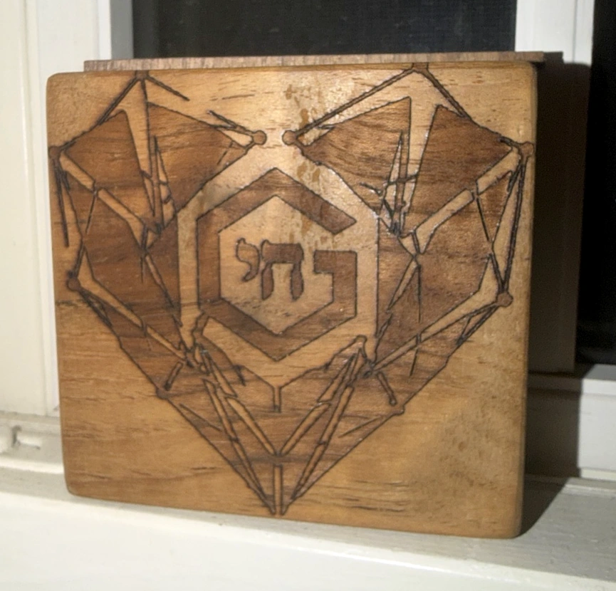 Square wooden plaque engraved with geometric heart imagery and a G Benincasa mark.