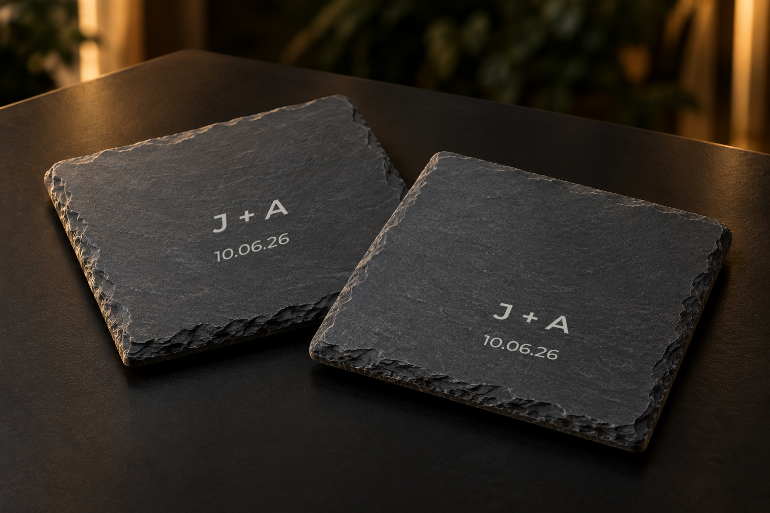 Illustrative concept of two dark slate coasters with matching initials and date.